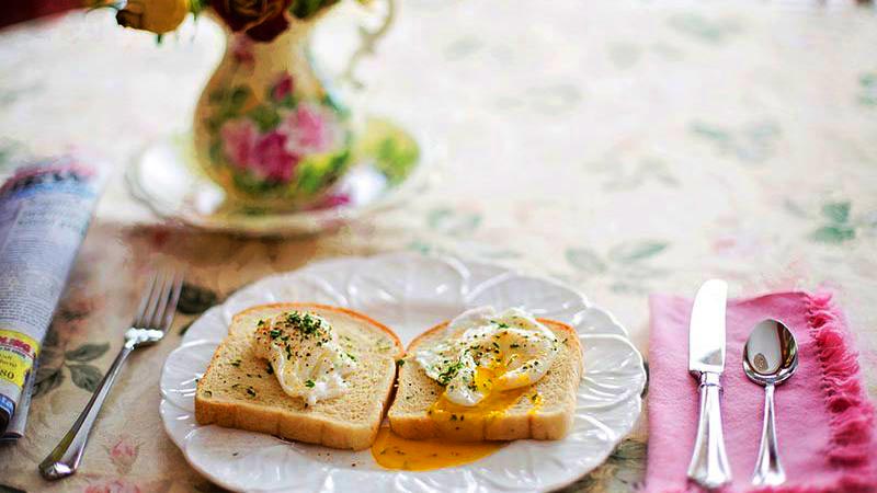 dos rebanadas de pan con huevos escalfados en un plato blanco con decoraciones