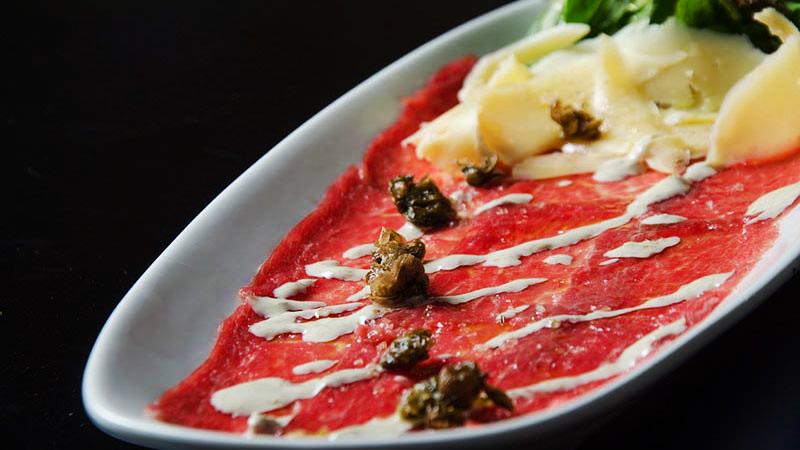carpaccio en un plato blanco y en un fondo negro