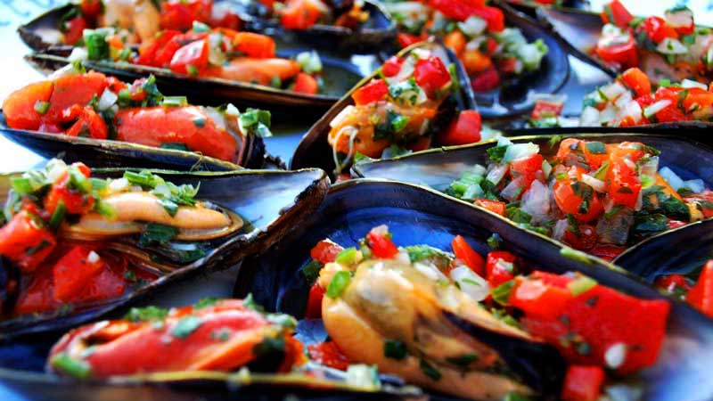 mejillones unos encima de otro con ajo y verduras