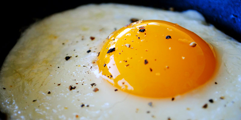 huevo frito muy de cerca con un poco de fondo azul marino