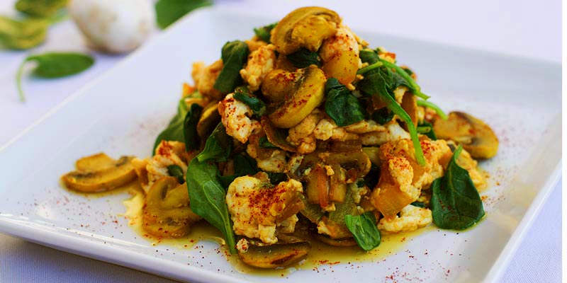 revuelto de huevo, setas y verdura sobre un plato blanco cuadrado