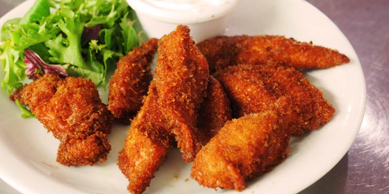 filetes de pollo rebozado en un plato blanco con ensalada