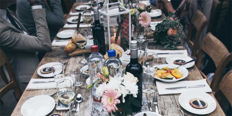 Mesa con muchos platos, botellas, copas y cubertería puesta
