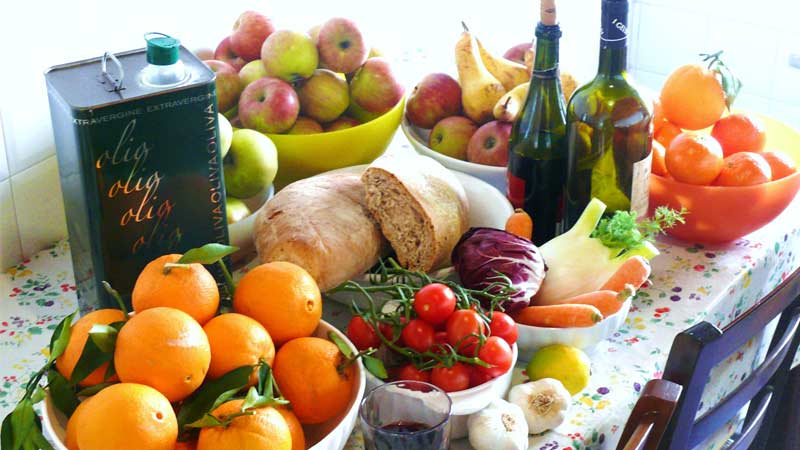 Frutas y verduras sobre una mesa junto a vino y aceite