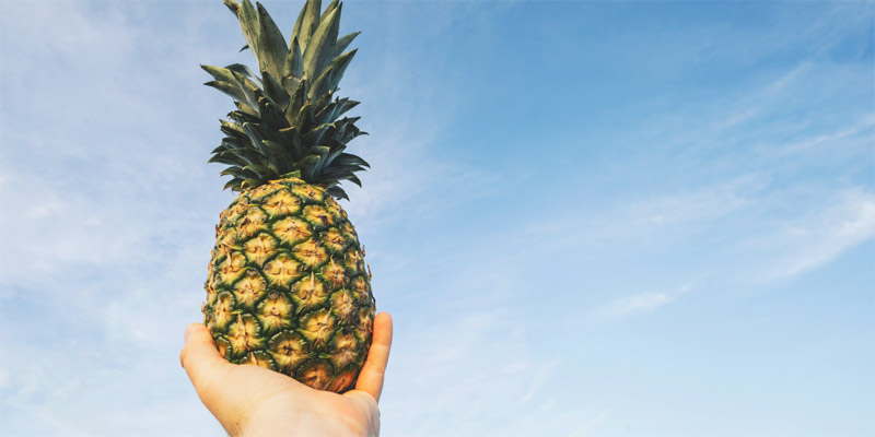 Una mano sujetando una piña en brazos
